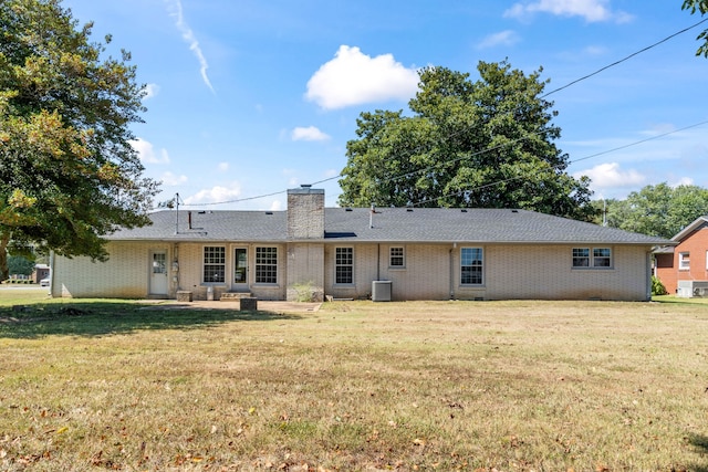 rear view of house with central AC unit and a lawn