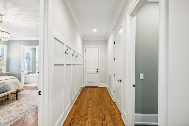 hall featuring crown molding, hardwood / wood-style floors, and an inviting chandelier