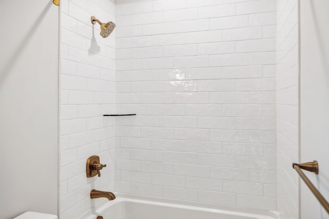 bathroom with toilet and tiled shower / bath