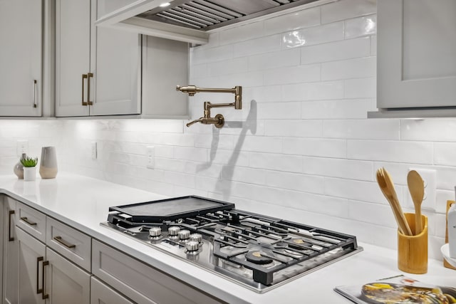 kitchen with gray cabinetry, decorative backsplash, custom range hood, and stainless steel gas cooktop