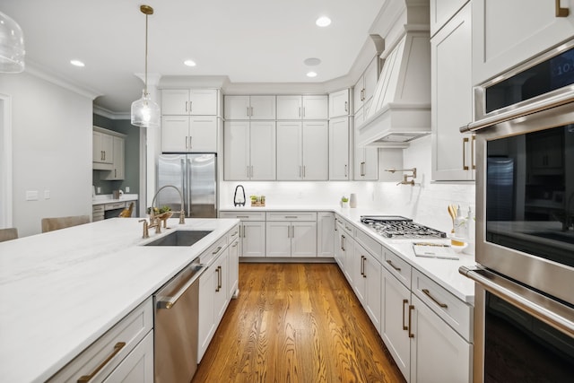 kitchen featuring appliances with stainless steel finishes, light wood-type flooring, sink, pendant lighting, and white cabinets