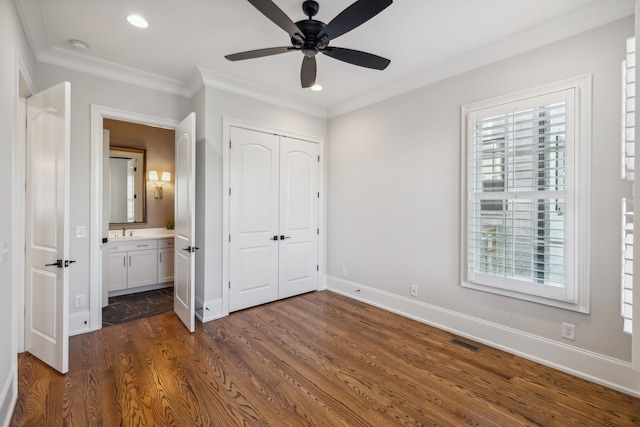 unfurnished bedroom featuring dark hardwood / wood-style flooring, ensuite bathroom, ornamental molding, ceiling fan, and sink