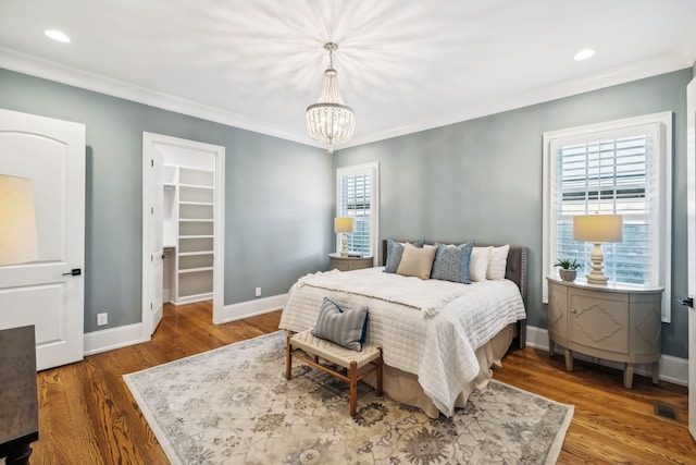 bedroom featuring a spacious closet, dark hardwood / wood-style flooring, and ornamental molding