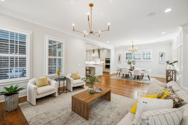 living room with light wood-type flooring, an inviting chandelier, and ornamental molding