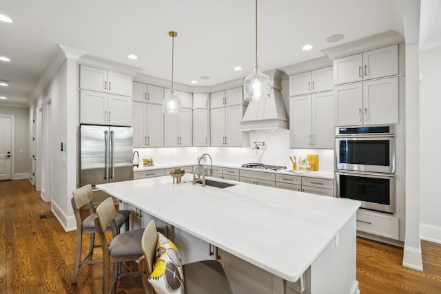 kitchen featuring sink, dark hardwood / wood-style floors, pendant lighting, custom exhaust hood, and appliances with stainless steel finishes