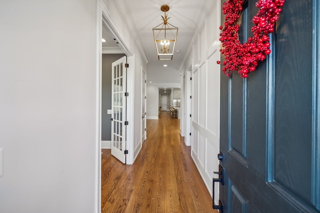 hall with hardwood / wood-style flooring, an inviting chandelier, and crown molding