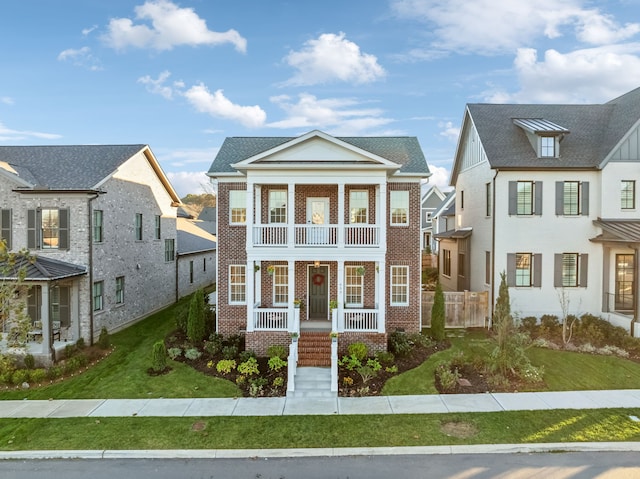 view of front facade with a balcony, a front lawn, and covered porch