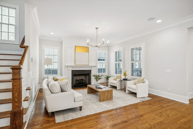 living room with crown molding, a chandelier, and light wood-type flooring