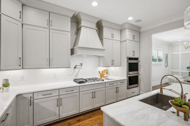 kitchen featuring sink, dark wood-type flooring, ornamental molding, premium range hood, and appliances with stainless steel finishes