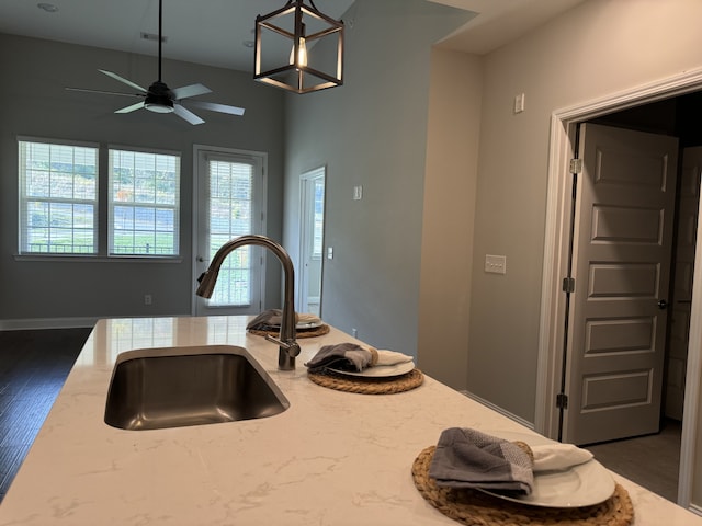 kitchen featuring sink, ceiling fan, light stone counters, decorative light fixtures, and dark hardwood / wood-style flooring