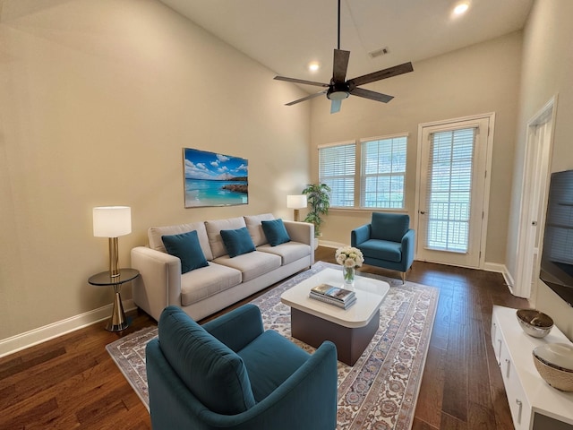 living room featuring ceiling fan, dark hardwood / wood-style flooring, and a towering ceiling