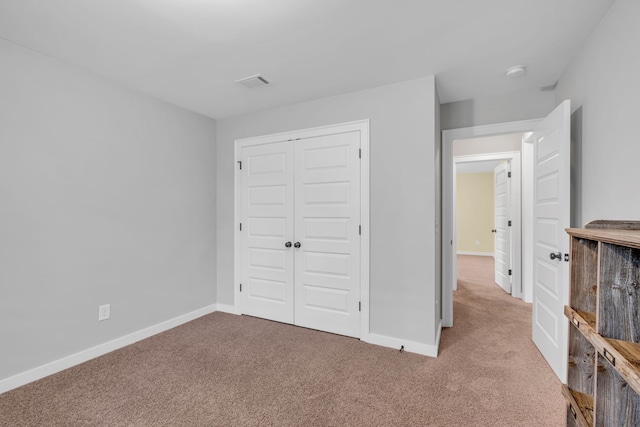 unfurnished bedroom with light colored carpet and a closet