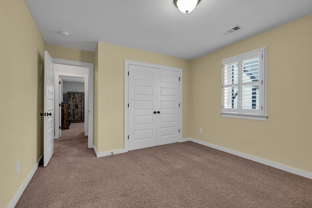 unfurnished bedroom with light colored carpet and a closet