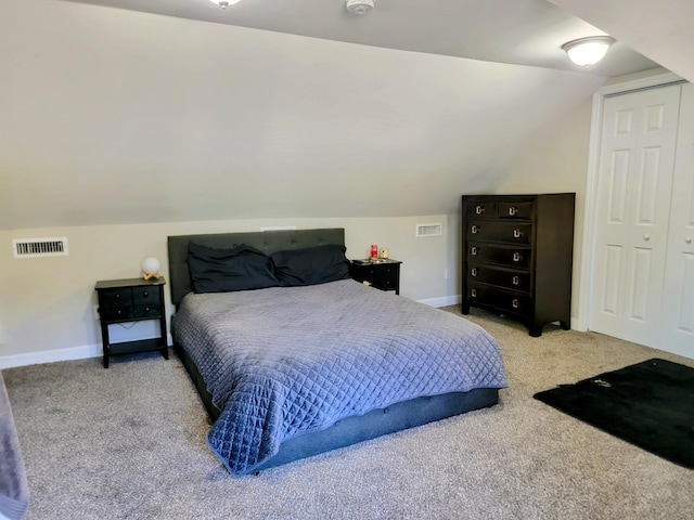 bedroom with light colored carpet, lofted ceiling, and a closet