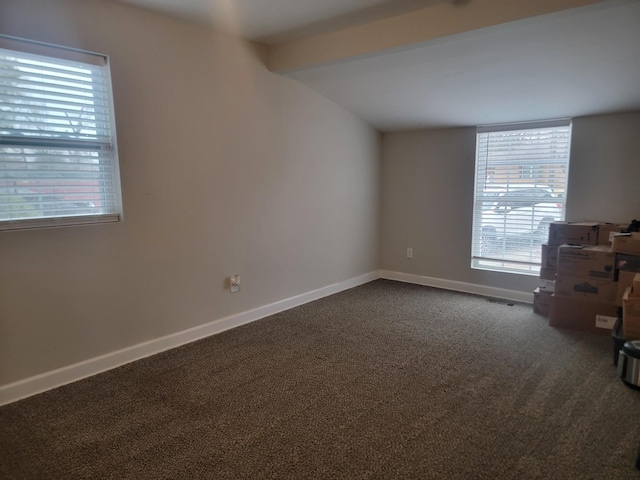 carpeted empty room featuring beam ceiling