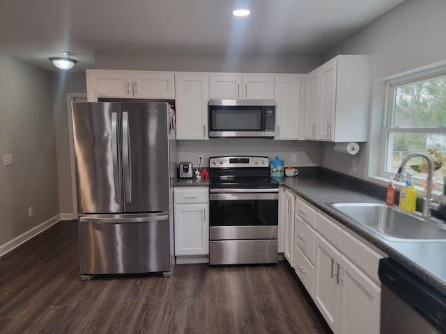 kitchen featuring appliances with stainless steel finishes, dark hardwood / wood-style flooring, sink, and white cabinets