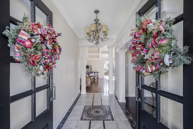 hall featuring dark wood-type flooring, french doors, crown molding, a notable chandelier, and decorative columns