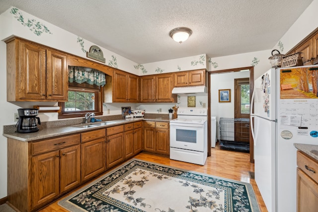 kitchen featuring a textured ceiling, sink, white appliances, and light wood-type flooring