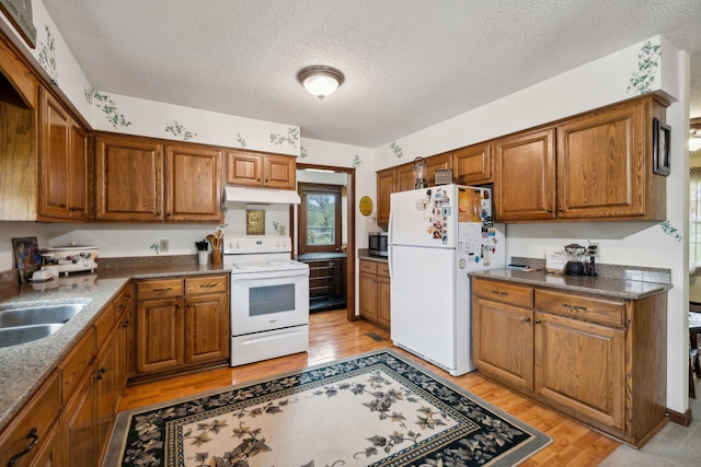 kitchen with a textured ceiling, sink, light hardwood / wood-style floors, and white appliances