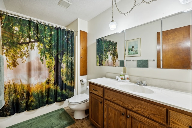 bathroom with vanity, toilet, and a textured ceiling