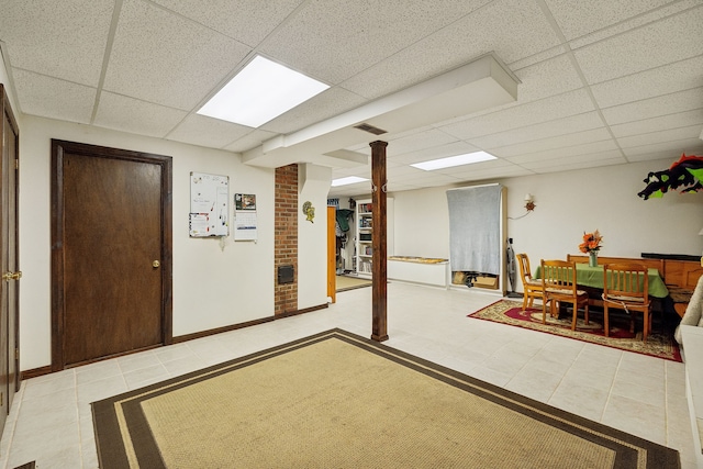 basement with a paneled ceiling and light tile patterned floors