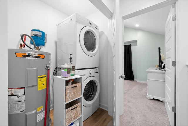 laundry room featuring water heater, stacked washer and dryer, and light carpet