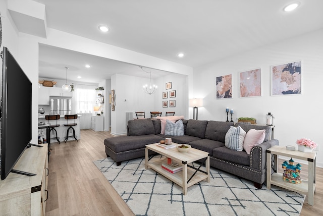 living room featuring light wood-type flooring and a notable chandelier