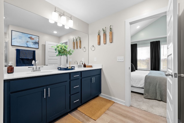 bathroom featuring hardwood / wood-style flooring, vanity, and vaulted ceiling