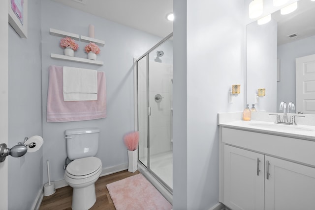 bathroom with hardwood / wood-style floors, vanity, toilet, and a shower with shower door