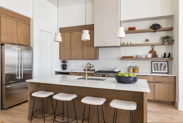 kitchen with sink, decorative light fixtures, light wood-type flooring, backsplash, and high end fridge