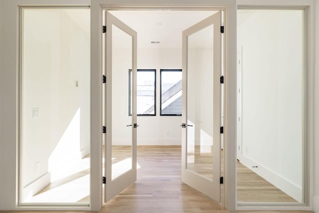 corridor with french doors and light hardwood / wood-style flooring