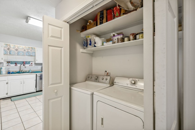 laundry room featuring a textured ceiling, light tile patterned flooring, washing machine and dryer, and sink