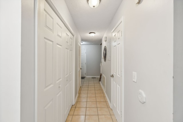 corridor featuring light tile patterned flooring and a textured ceiling