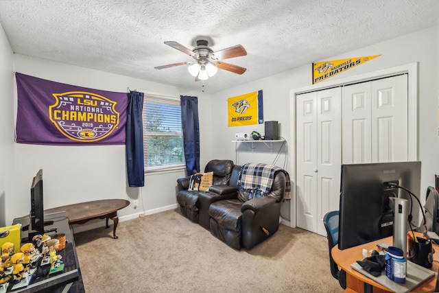 sitting room featuring ceiling fan, carpet, and a textured ceiling