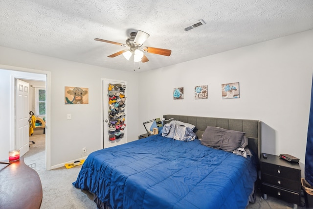 carpeted bedroom with ceiling fan and a textured ceiling