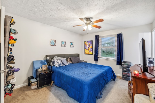 bedroom with ceiling fan, light colored carpet, and a textured ceiling