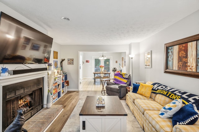 living room featuring a textured ceiling, an inviting chandelier, and light hardwood / wood-style flooring