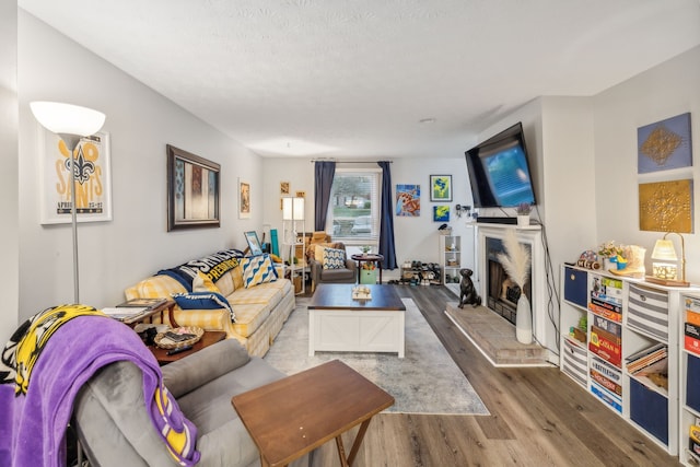 living room featuring a fireplace, a textured ceiling, and hardwood / wood-style flooring