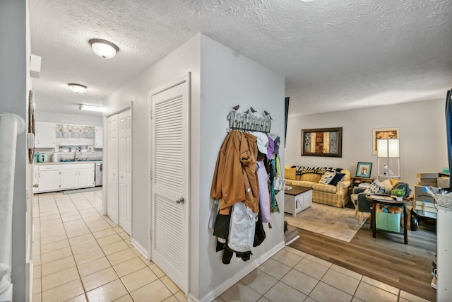 hallway featuring a textured ceiling, light hardwood / wood-style floors, and sink