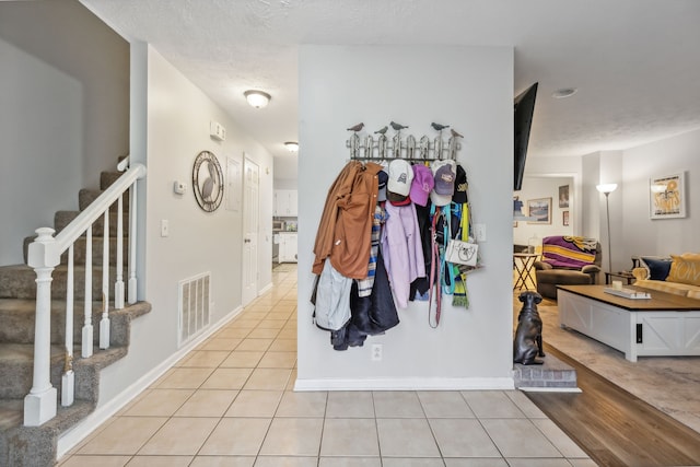 entryway featuring light tile patterned floors and a textured ceiling