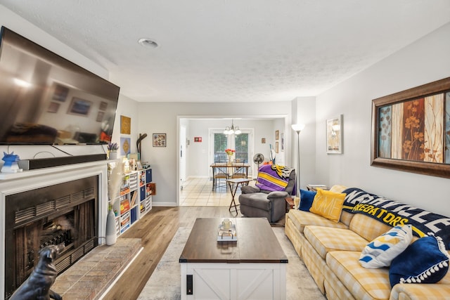 living room featuring light hardwood / wood-style floors, a textured ceiling, and a notable chandelier