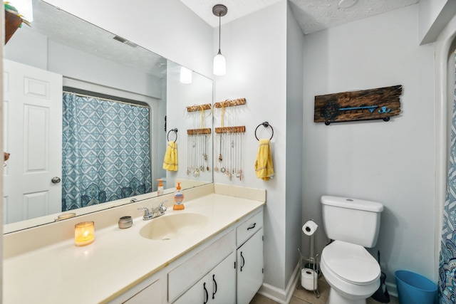 bathroom featuring tile patterned flooring, a textured ceiling, vanity, and toilet