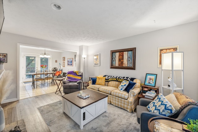 living room featuring a textured ceiling, light hardwood / wood-style flooring, and a notable chandelier