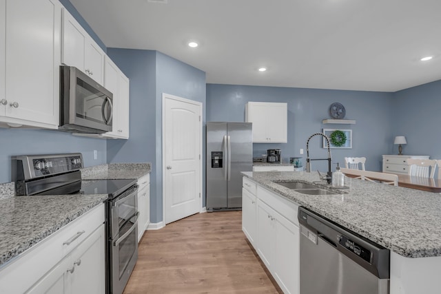 kitchen featuring appliances with stainless steel finishes, white cabinetry, a kitchen island with sink, and sink