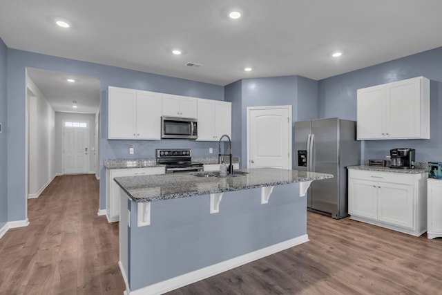 kitchen with sink, white cabinetry, stainless steel appliances, and a kitchen island with sink