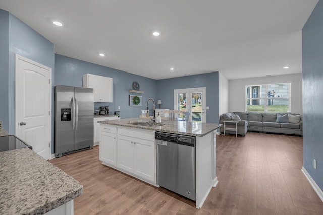 kitchen featuring sink, an island with sink, light hardwood / wood-style floors, white cabinetry, and stainless steel appliances