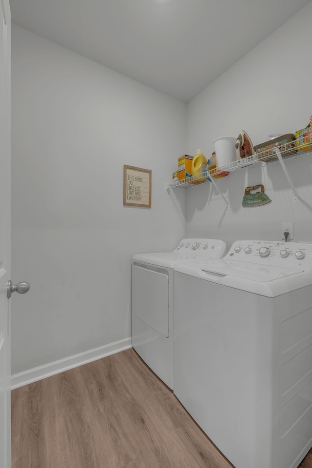 laundry area with washing machine and dryer and light hardwood / wood-style flooring