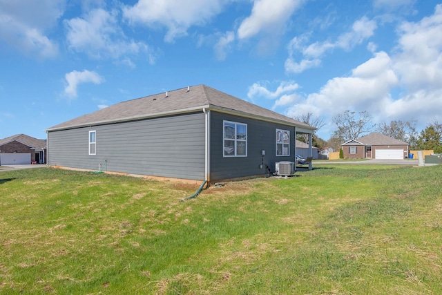 view of side of home featuring a garage, a yard, and central AC