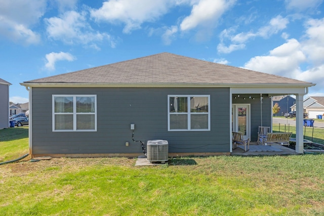 rear view of house featuring central AC unit and a lawn