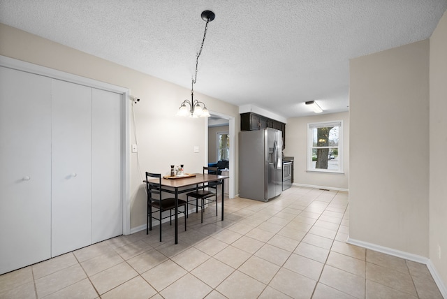 dining space featuring light tile patterned floors, a textured ceiling, and a notable chandelier